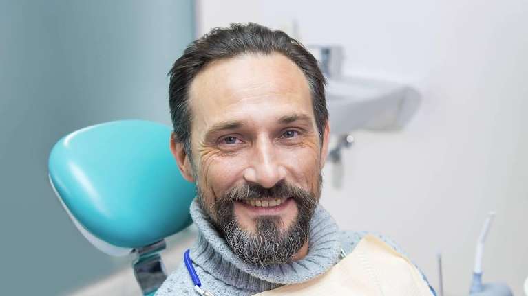 Older man smiling in dental chair, charlotte nc