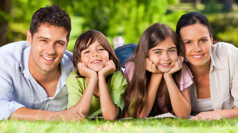 Family smiling together laying on the grass, charlotte nc